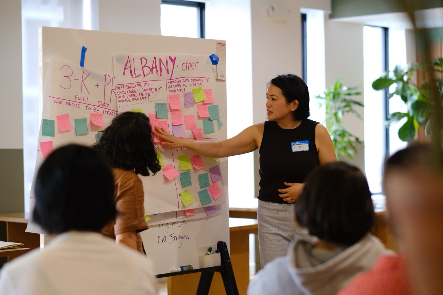 An organizer maps out a plan on a sticky-note-covered flip chart at a New Yorkers United for Child Care strategy meeting.
