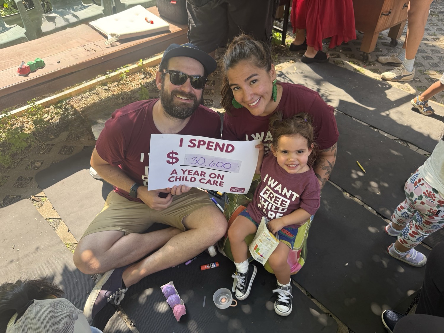 A mom and dad sit with their toddler at a New Yorkers United for Child Care event.